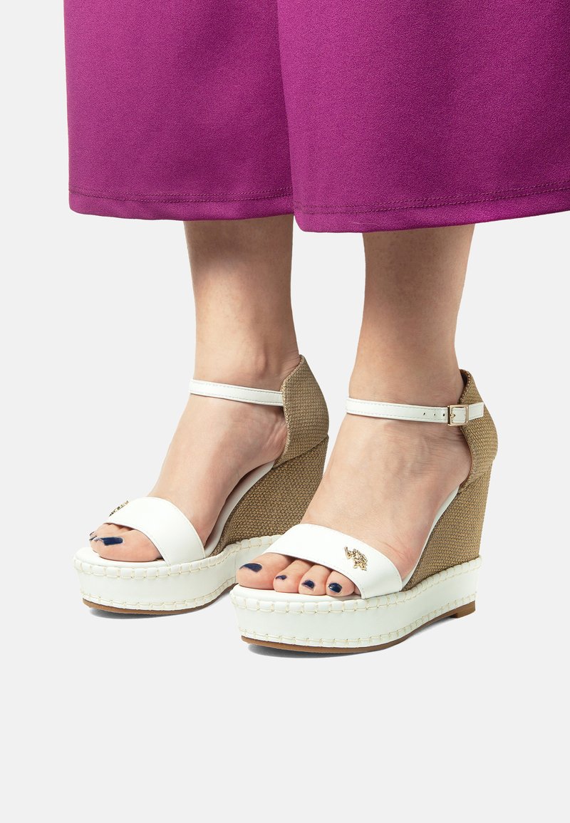 Sandali wedge bianchi con una base marrone texturizzata, dotati di una cinghia alla caviglia e design con punta aperta. Dettagli in oro sulla cinghia anteriore.