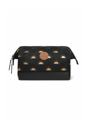 Trousse de maquillage noire ornée d'un motif solaire doré. Le matériau est un tissu avec un accent en cuir à la base. Ouverture zippée et détail de marque.