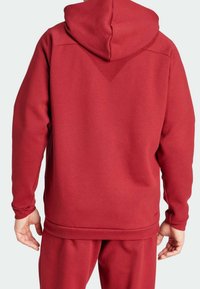 Red fleece hoodie with a drawstring hood, ribbed cuffs, and hem. Smooth texture, simple design, and a relaxed fit.