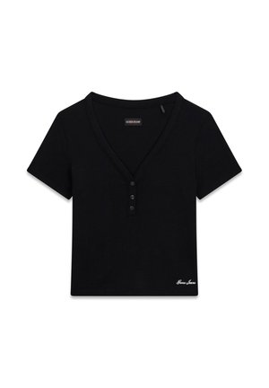 Top corto nero a maniche corte stile Henley con scollo a V, tre bottoni e logo "Guess Jeans" ricamato in basso a destra.