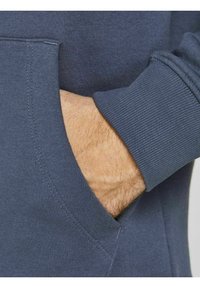 Dark gray hoodie with a front pocket, showing a hand resting in the pocket. Smooth fabric with ribbed cuffs and stitching details.