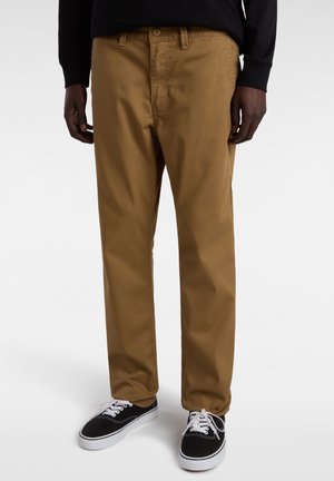 Braune Baumwoll-Chinos mit geradem Schnitt, mit einem Knopfverschluss und seitlichen Taschen. Kombiniert mit schwarzen Schnürsneakers.