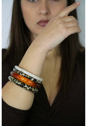 Set of four bangles on an arm: two clear plastic, one orange, and one black with a leopard pattern, featuring smooth and glossy textures.