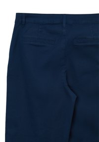 Pantalons bleu marine en tissu lisse, dotés de deux poches arrière et d'une coupe ajustée. Pas de détails en métal visibles.