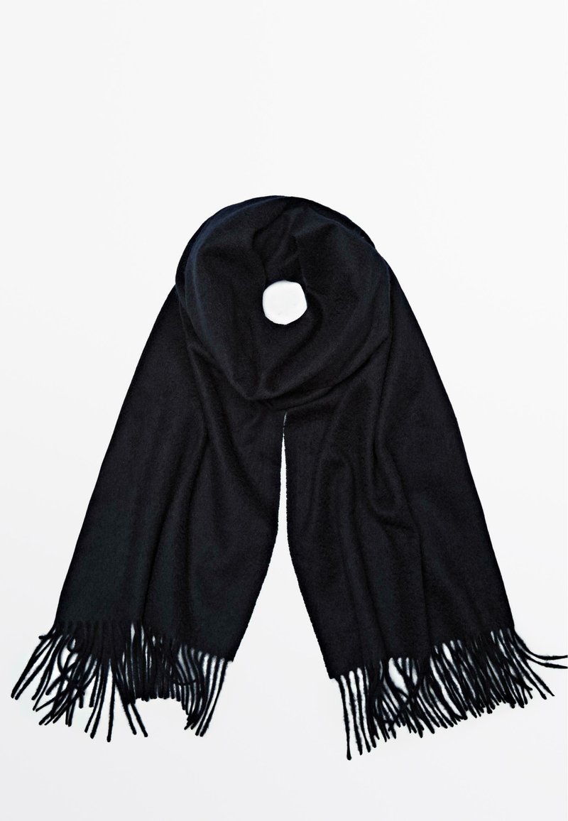 Svart scarf av mjukt tyg, med ett cirkulärt hål och långa fransar i ändarna, utbrett på en vit bakgrund.