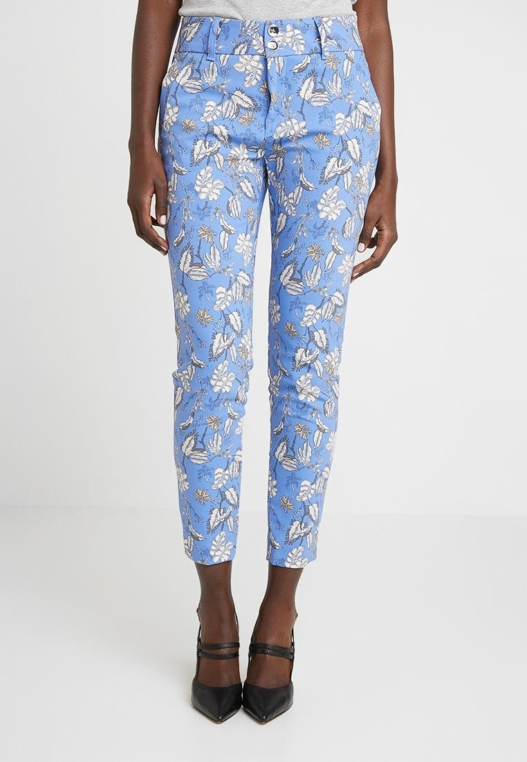 Blue floral patterned pants featuring a tapered fit, two front buttons, and a smooth texture, paired with black pointed heels.