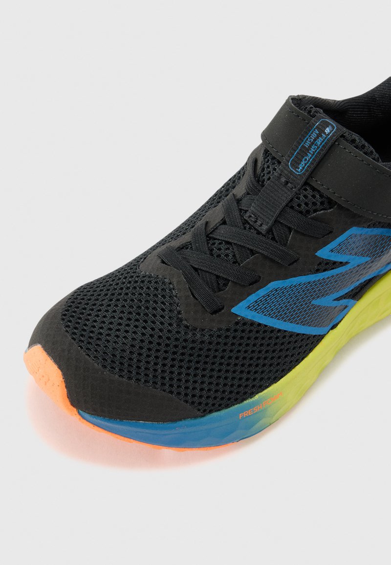 Zapatilla de correr de malla negra con acentos azules, puntera naranja y suela verde. Presenta una correa y cordones tradicionales para un ajuste seguro.