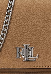 Tan lædertaske med en sølvfarvet kædetras og RL-logo hardware med en struktureret overflade.