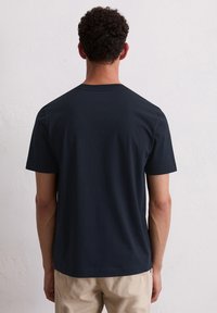 Marineblaue kurzärmlige Baumwoll-T-Shirt mit Rundhalsausschnitt, glatter Textur und geradem Schnitt, von hinten betrachtet.