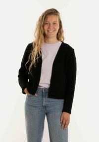Zwarte gebreide cardigan met lange mouwen, open voorkant, gedragen over een lichtpaarse t-shirt en blauwe high-waisted jeans. Gladde textuur.