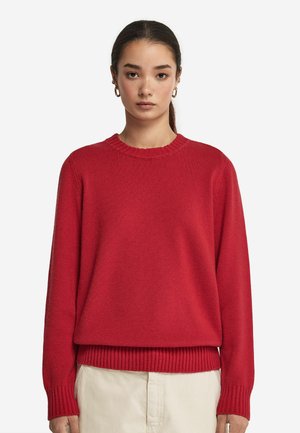 Rød strikket sweater med rund halsudskæring, ribbede manchetter og kant. Stoffet har en blød tekstur og en afslappet pasform.