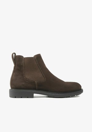 Stivali ankle in suede marrone con punta tonda, pannelli elasticizzati ai lati e una linguetta sul retro. Suola in gomma spessa e texturizzata.