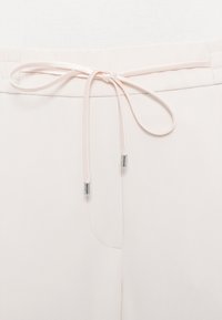 Pantaloni jogger roz deschis cu talie cu șnur, textură fină a materialului și detalii subtile de cusături.