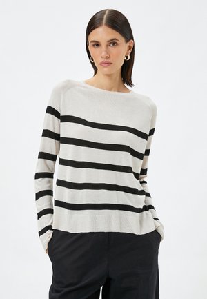 Lys beige sweater med sorte horisontale striber. Har en rund halsudskæring, lange ærmer og et struktureret strikkemateriale.