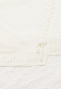 Maglione bianco lavorato a maglia con motivo testurizzato, presenta bordi a coste e un piccolo dettaglio annodato. Materiale morbido e peloso con una leggera lucentezza.