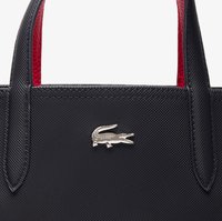 Sac fourre-tout noir texturé avec des accents rouges, arborant un logo crocodile métallique argenté. Les poignées sont robustes et de forme rectangulaire.