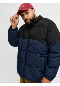 Steppjacke mit durchgehendem Reißverschluss, obere Sektion in Schwarz, untere Sektion in Marineblau, mit gesteppter Textur und elastischen Bündchen.