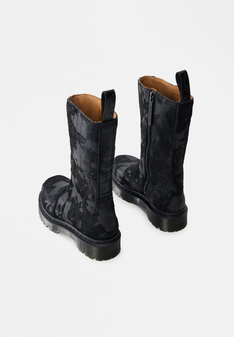 Coppia di stivali neri a metà polpaccio con motivo floreale testurizzato, cerniera laterale, linguette per tirare e suole spesse traslucide su sfondo bianco.