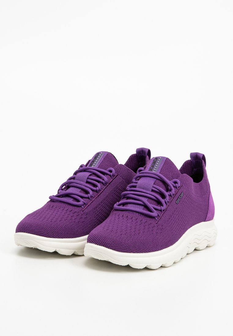 Un paio di scarpe sportive in rete viola con suole in gomma bianca e stringhe viola coordinate, angolate per mostrare le viste frontale e laterale.