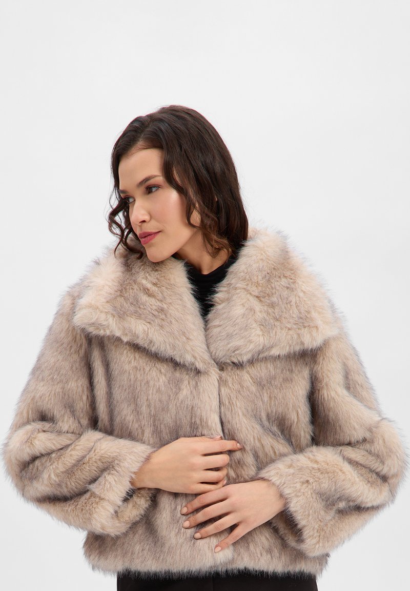 Chaqueta de piel sintética en beige claro con un amplio cuello, diseño corto y mangas anchas. Presenta una textura suave y cierre de botones.