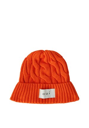 Bonnet tricoté orange vif avec un gros motif torsadé et un bord côtelé replié, avec un patch blanc étiqueté "oui" en texte noir.