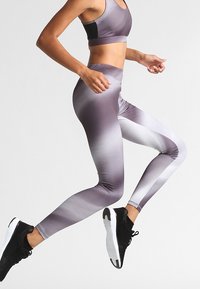 Legginsy z wysokim stanem w gradientowym wzorze w odcieniach szarości, wykonane z elastycznego materiału. Posiadają dopasowany krój i gładką teksturę.