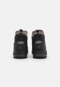 Czarne wodoodporne buty trekkingowe z szarym kołnierzem z sztucznego futra, wzmocnionym piętą i teksturowaną gumową podeszwą, zaprojektowane z myślą o przyczepności i trwałości.
