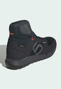 Czarne wysokie buty sportowe z oddychającą siateczką, teksturowanymi akcentami, wodoodporną etykietą Gore-Tex i kontrastującymi czerwonymi detalami.