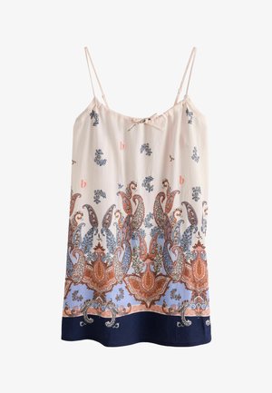 Nahaufnahme einer Hand, die den Saum eines gemusterten Kleides mit blauen, rosa und beigen Paisley-Mustern und einem kleinen goldenen Logo-Anhänger hält.