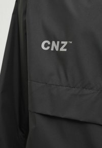 Zwarte windbreaker met een soepele, lichtgewicht stof. Opvallend detail is het zilveren "CNZ" logo op de borst.