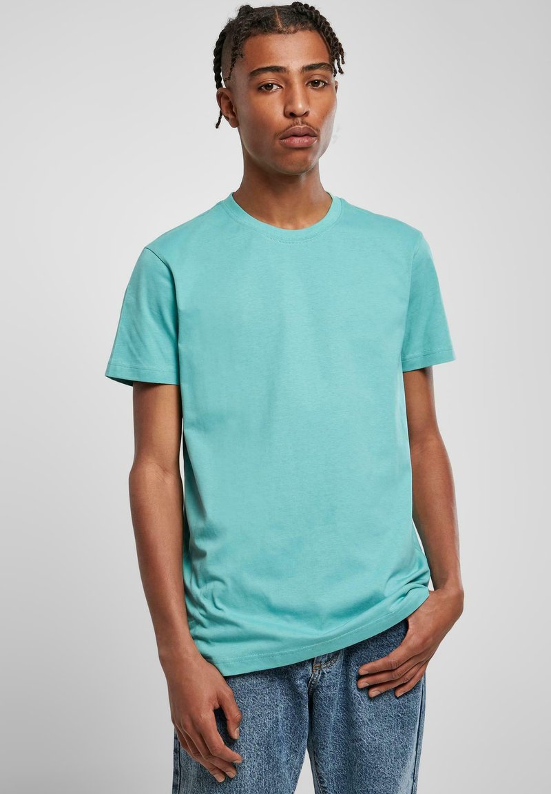 Tricou cu mânecă scurtă și guler rotund, din bumbac turcoaz deschis, având o textură fină și o croială lejeră. Asortat cu blugi decolorati.