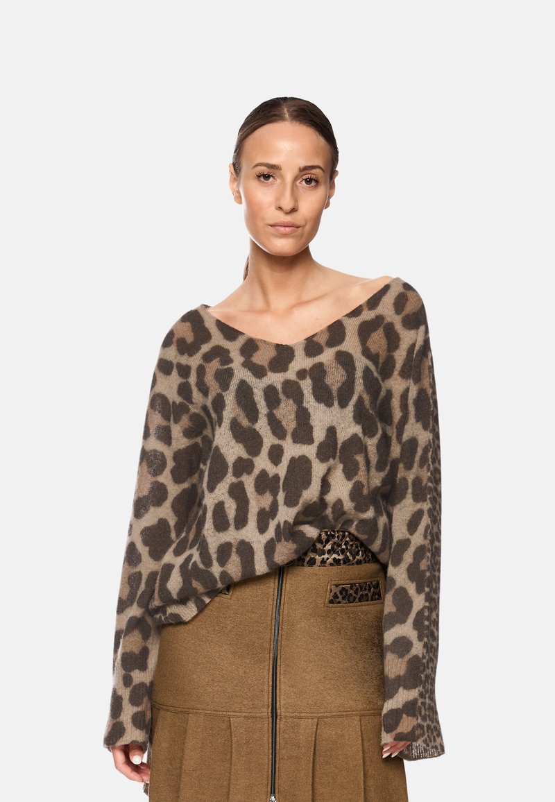 Beige und braun gemusterter Strickpullover im Leopardenlook mit lockerer Passform, weitem V-Ausschnitt und langen Ärmeln, kombiniert mit einem braunen Faltenrock.