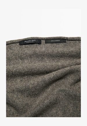 Sciarpa grigia in cashmere con un aspetto morbido e testurizzato, con etichette visibili che indicano marca e composizione del materiale.