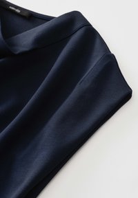 Marineblaues Poloshirt mit glatter Textur, umgeschlagenen Ärmeln und klassischem Kragendesign. Das Material wirkt weich und leicht.