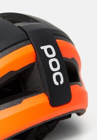 Casco de bicicleta negro y naranja con superficie texturizada, ranuras de ventilación y una insignia de logo. Acabados suaves con mecanismo de ajuste.