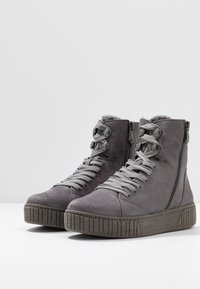 Baskets montantes en daim gris avec semelles en caoutchouc texturées, dotées d'une fermeture éclair et d'un design à lacets, complétées par des lacets et des accents gris.