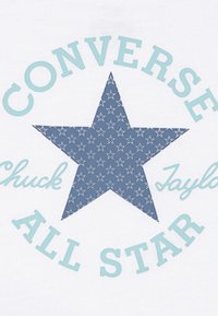 Bílá látka s modrou hvězdou s květinovým vzorem, obklopená textem "CONVERSE" a "Chuck Taylor" ve světle modré barvě.
