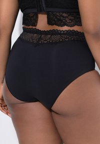 Culotte noire taille haute en tissu lisse, avec une ceinture décorative en dentelle et un détail au dos.