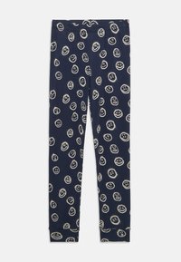 Leggings bleu marine en tissu doux, ornés de motifs de visages souriants blancs. Design ajusté avec des poignets à la cheville pour un maintien confortable.