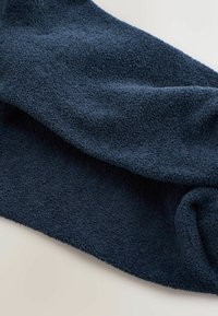 Granatowy polar o teksturowanej, miękkiej powierzchni, z delikatnym połyskiem. Materiał wydaje się lekki i swobodnie się układa.