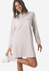 Lys grå langærmet natkjole med nøglehul-nakke, med subtile stjerne mønstre, og parret med hvide teksturerede sokker og tøfler.