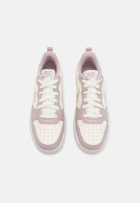 Baskets Nike blanches et rose pâle en mesh et cuir, à bout rond, avec des détails perforés et des lacets et accents contrastés.
