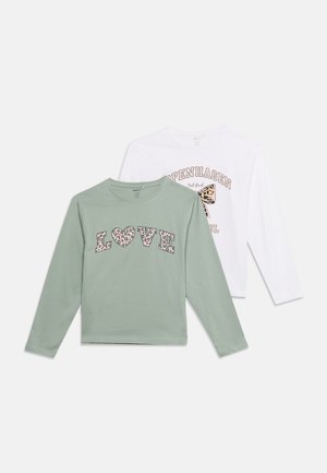 Deux chemises à manches longues, une vert clair avec "LOVE" en lettres imprimées léopard, une blanche avec le texte "COPENHAGEN" et un nœud imprimé léopard.