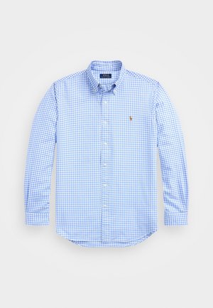 Chemise à manches longues boutonnée en vichy bleu clair et blanc avec col et petit logo brodé sur la poitrine gauche.