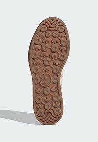 Hnedá gumová podrážka s kruhovým vzorom gripu, na ktorej sa nachádza centrálne logo. Hladký povrch s zaobleným tvarom a kontrastnými farebnými akcentmi.