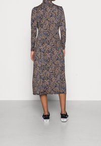 Abito a maniche lunghe stampato con collo alto, in un motivo leopardato blu e marrone, con una vestibilità ampia che scende sotto il ginocchio.