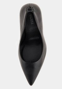 Chaussure plate en cuir noire à bout pointu avec logo GUESS sur la semelle intérieure rembourrée et petit détail de boucle métallique près du talon.