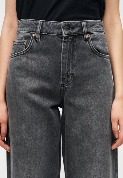 Γκρι τζιν με ψηλή μέση και χαλαρή εφαρμογή, με πέντε τσέπες, κλείσιμο με κουμπί και διακριτική ξεθώριασμα σε όλο το ύφασμα.