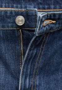 Jeans en denim bleu foncé avec un bouton et une fermeture éclair en argent. Couture orange marquée le long des coutures et des poches. Texture lisse.