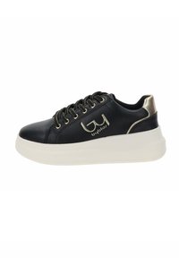 Sneaker nera in pelle con suola bianca spessa, dettagli in tonalità oro e design con lacci. Caratterizzata da un logo vicino al tallone e una parte superiore a trama.